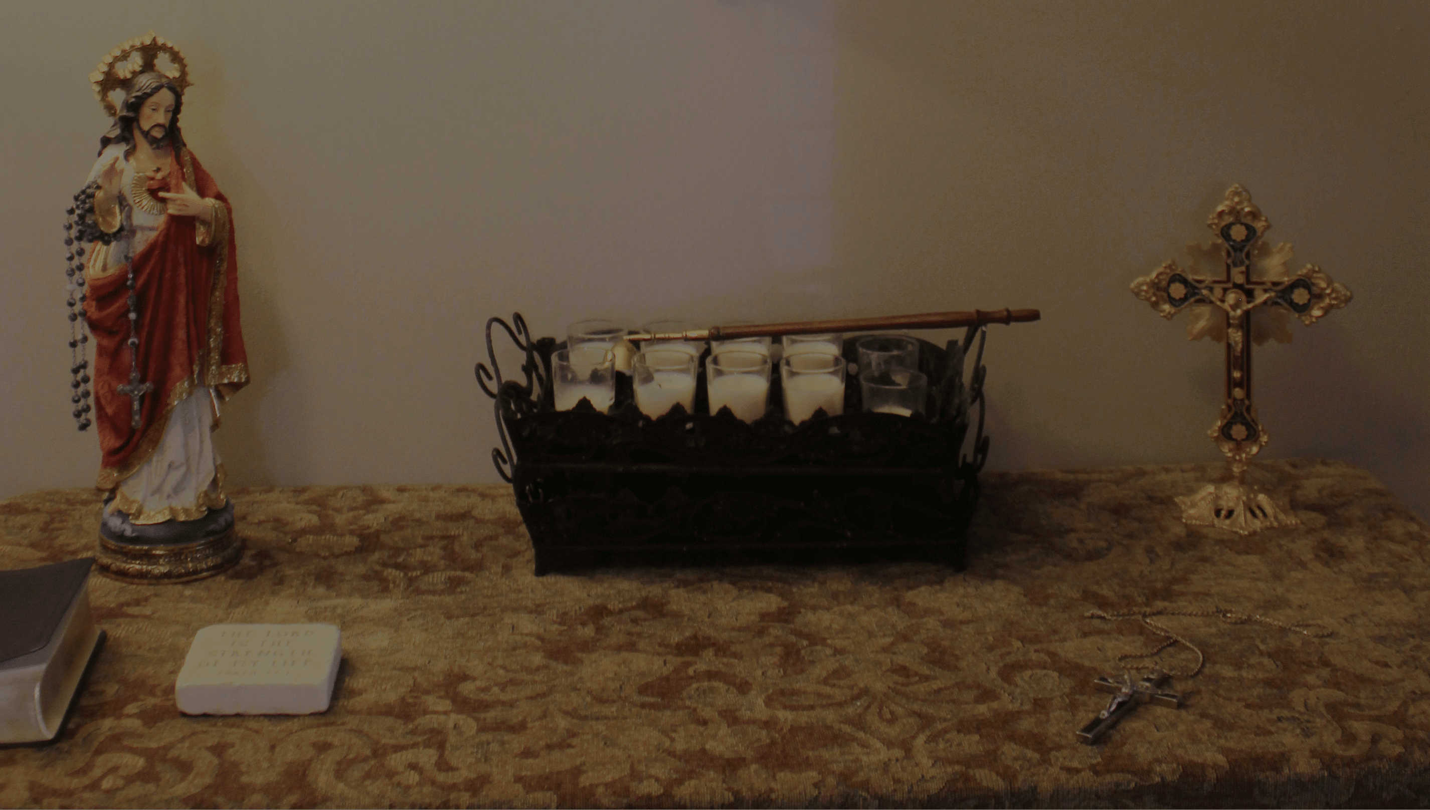 Cross above table with figurine of jesus on it.